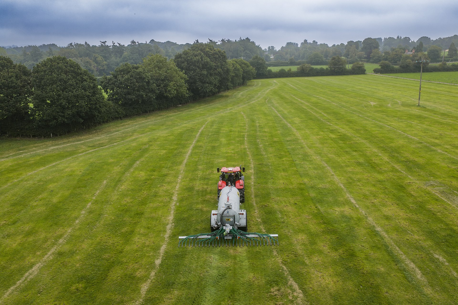 A tractor applying slurry through trailing hoses on grassland